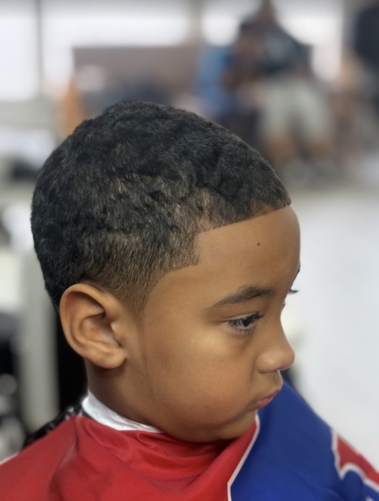 Barber calmly talking with a young boy before his kids haircut at Verified Cuts 2 in Fort Mill.